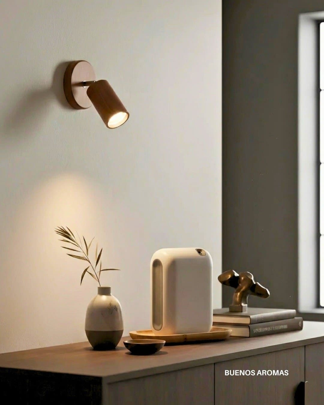 Equipo aromatizador chico sobre un mueble, junto a una lámpara de luz cálida
